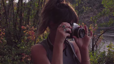 linda chica hipster explorando un parque y tomando fotos en una cámara de cine