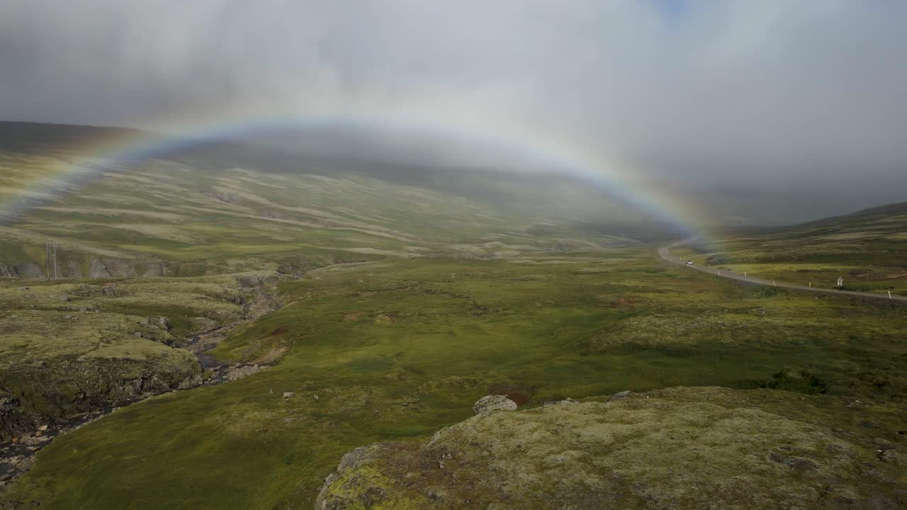 Unveil a surprise rainbow emerging through the fog atop an Icelandic mountain, post-rainstorm &mdash; a mystical moment in crisp 4K, captured by drone