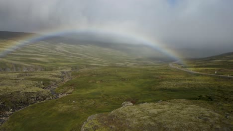desvelar un arco iris sorpresa emergiendo a través de la niebla en lo alto de una montaña islandesa, después de la tormenta  ⁇  un momento místico en 4k nítido, capturado por un dron