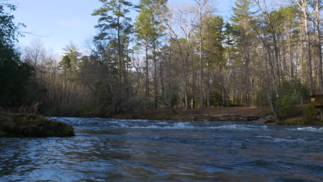 panning shot of a calm river in a forest at georgia during the winter