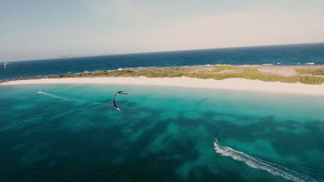 men kitesurfing along white sand beach, aerial view crasqui island los roques