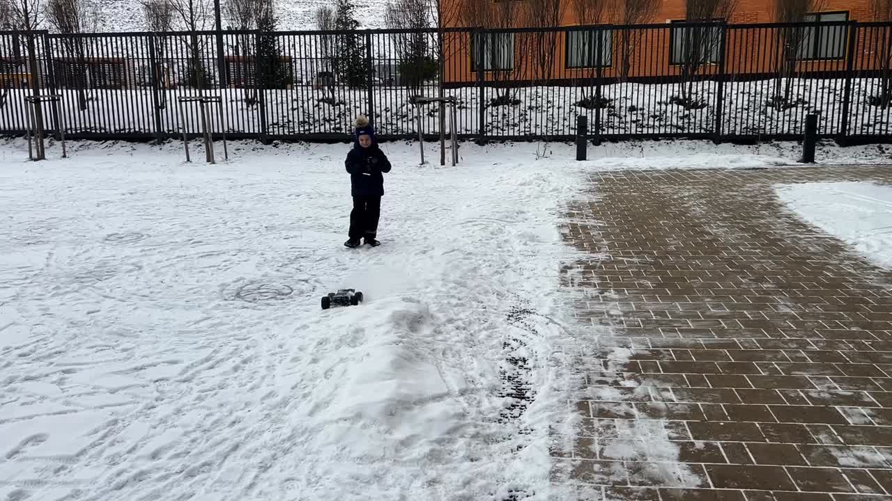 Child playing with a remote control car in the snow