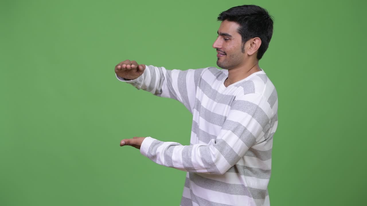 Young handsome Persian man showing something