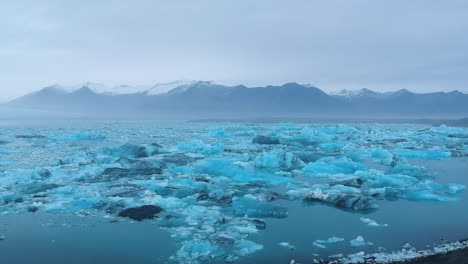 Wonderful-aerial-forward-view-of-a-lake-in-ice-landscape-with-a-man-from-the-headland-watches