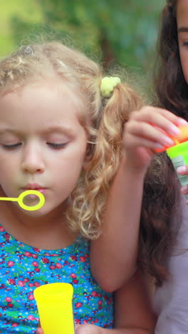 niños jugando con la varita de burbujas en el parque