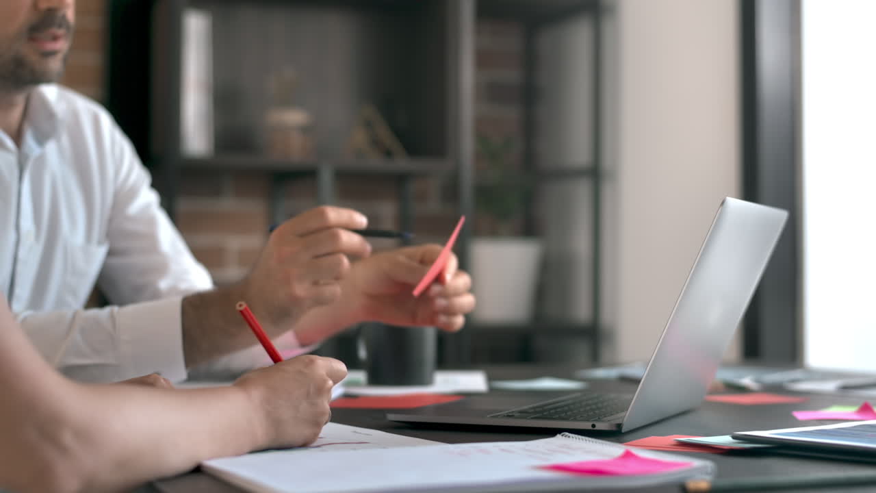 Una mujer y un hombre trabajando y hablando en la oficina. Dispositivos y documentos con información.