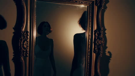 a woman's reflection in a dark, ornate mirror