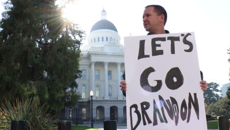 male political protester with let's go brandon sign