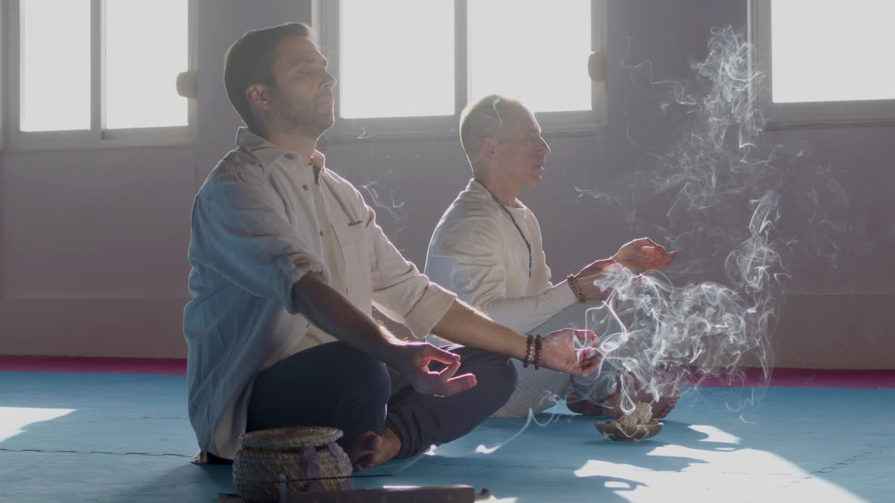 hombres caucásicos meditando con incienso en la habitación