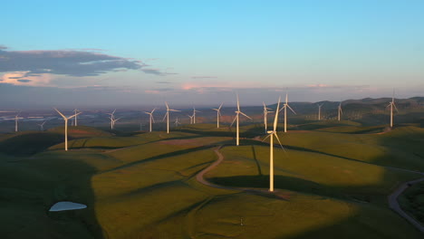 Aerial-tracking-shot-of-a-sunlit-wind-power-farm-in-the-mountains-of-California