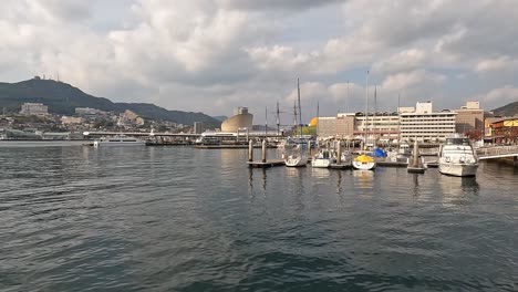 Blick-über-Das-Hafenbecken-Von-Nagasaki,-Japan,-Eröffnungsaufnahme-Mit-Booten-Und-Der-Uferpromenade