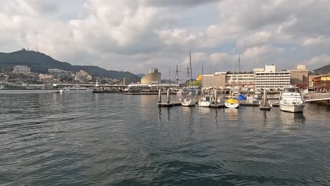 vista sobre la cuenca del puerto de nagasaki, japón, toma de apertura que muestra barcos y el paseo marítimo