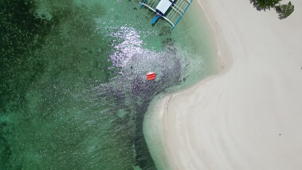 Drone bird's eye view of banca outrigger canoes on tropical white sandy beach