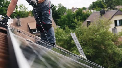 Man-carefully-lands-solar-panel-on-top-of-rooftop-into-place,-side-view