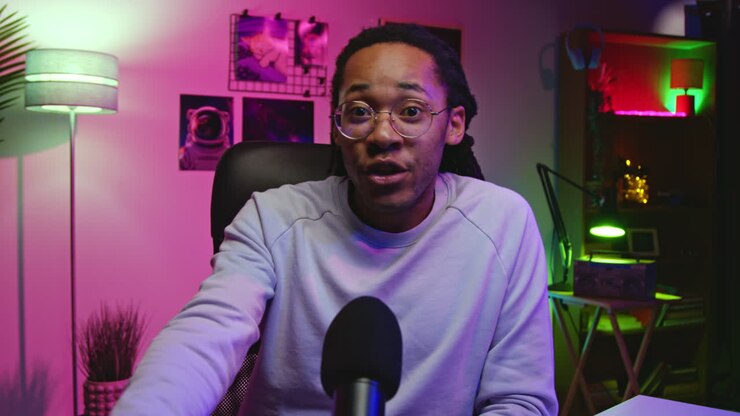 Uomo con capelli afro che parla in un microfono, probabilmente in streaming o podcasting