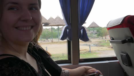 a girl watches birds and rhinos through a bus window