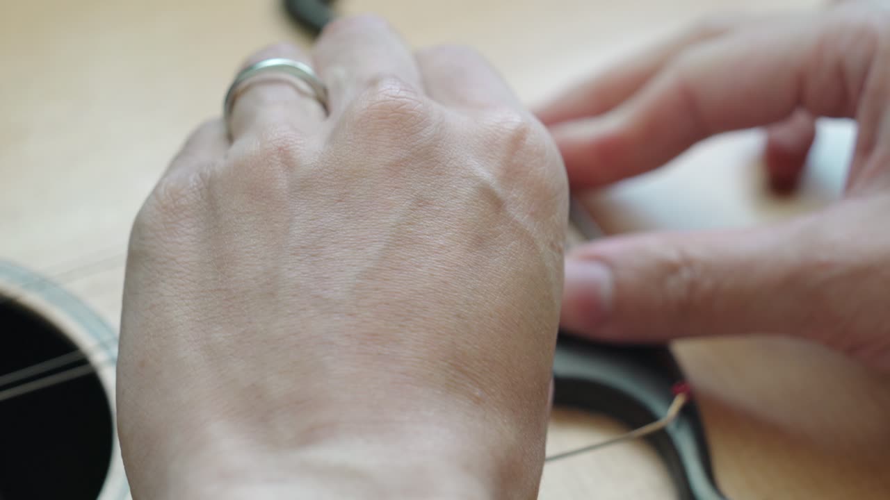 Hands Of A Luthier Removing Strings From The Guitar Bridge
