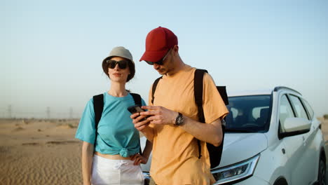 pareja usando un teléfono inteligente en el desierto