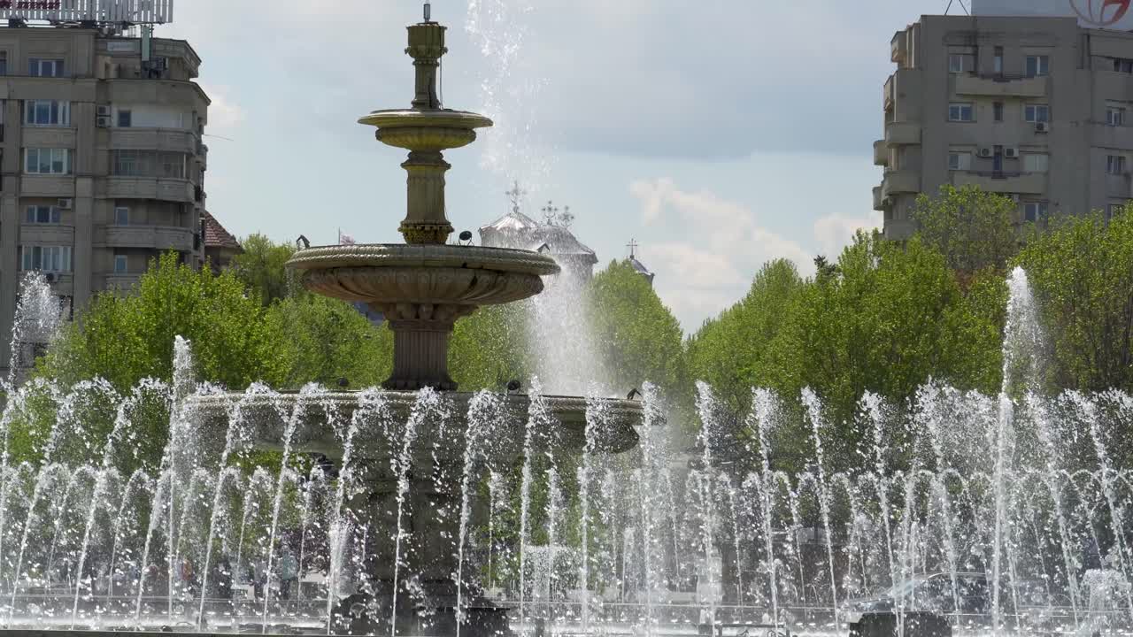 Fuente de agua con una iglesia de fondo, Plaza Unirii, Bucarest, Rumanía