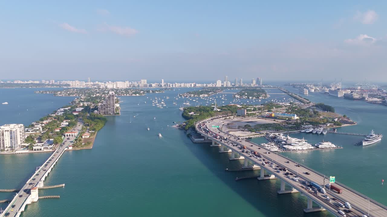 Aerial drone view of Miami’s scenic Venetian Causeway and Biscayne Bay, featuring luxury yachts, islands, and the city skyline under a clear blue sky.