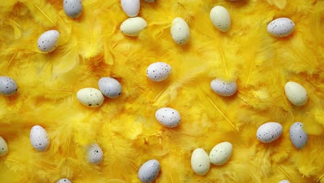 Composition-of-pastel-easter-eggs-lie-among-of-yellow-feathers-for-holidays