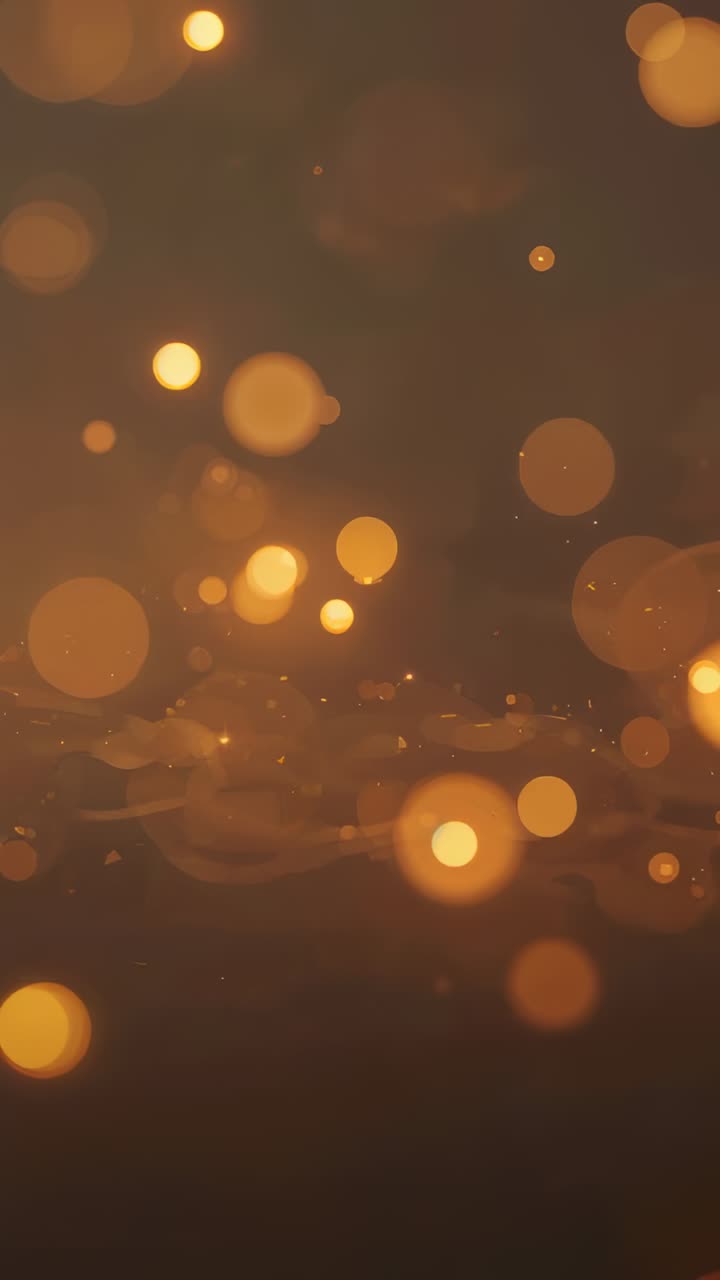 Vertical video: Looping, golden orbs, sparks and ribbon drifting over dark field, making warm glow