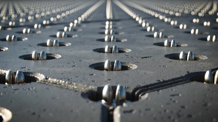 Moving low-angle camera pushing forward over rooftop, revealing metal studs, seams, cable, droplets