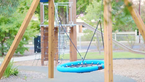 niños pequeños se balancean agitando en el patio de recreo de los niños con el poco día de lluvia y viento débil