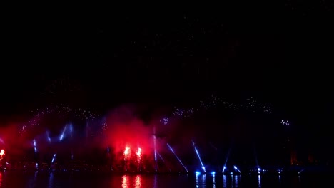 어두운 하늘에서 화려한 반사와 함께 화려한 불꽃놀이와 밝은 빛이 물 속에 아름답게 반사됩니다.