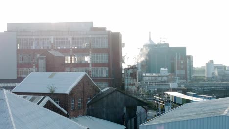 old industrial chemical warehouse buildings aerial view factory steam smoke emissions early morning slow right