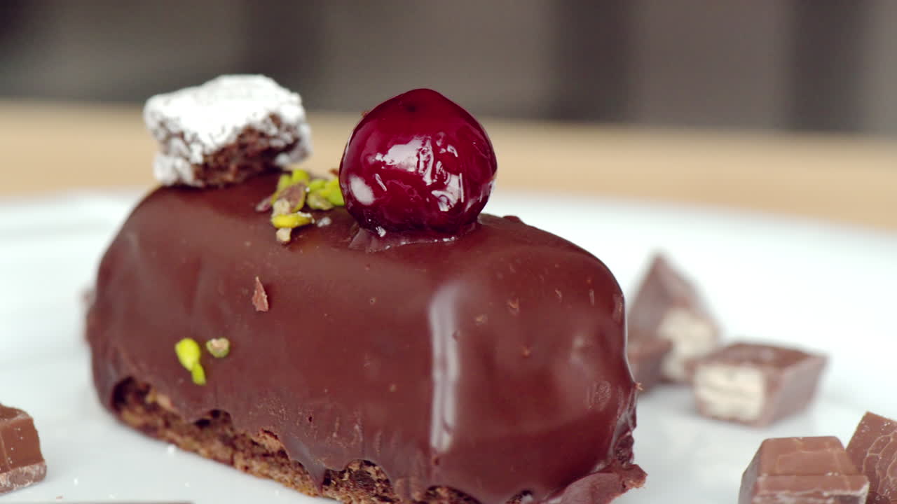 Moving chocolate cake with cherry on top, macro close up