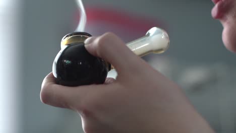 macro de una mujer fumando de una pipa negra
