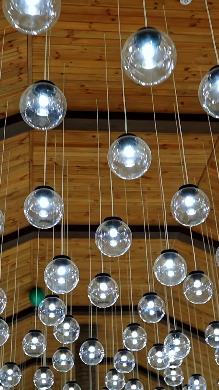 Luxury interior of glass light bulbs. Futuristic pendant lights of round shape. Many shiny balls on the ceiling background. Vertical video