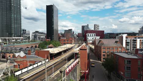 aerial drone flight passing over deansgate train station and heading over the rooftops towards oxford road in manchester city centre