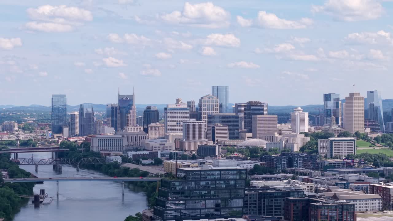 Looking along the Cumberland River from the Germantown neighborhood at the Nashville, Tennessee downtown city skyline at daytime - rising aerial reveal