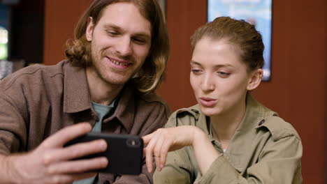 portrait of a happy couple taking a selfie with phone at the cinema