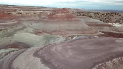 Orbit-Aerial-View-of-Man-Climbing-on-Striped-Sandstone-Hill-in-Utah-Desert-Ladnscape,-Hanksville-USA