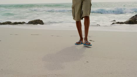 sección baja de un hombre caminando descalzo en la playa en un día soleado 4k