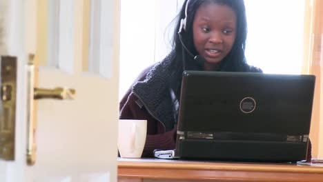 Laughing-woman-using-a-laptop-with-headset-on