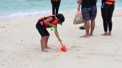 child digging sand with shovel on beach