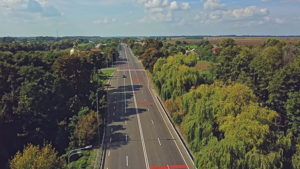 Aerial view through a quiet residential neighborhood along the main street of this small rural town on a clear day. Flying over a newly paved and empty main street in a rural town