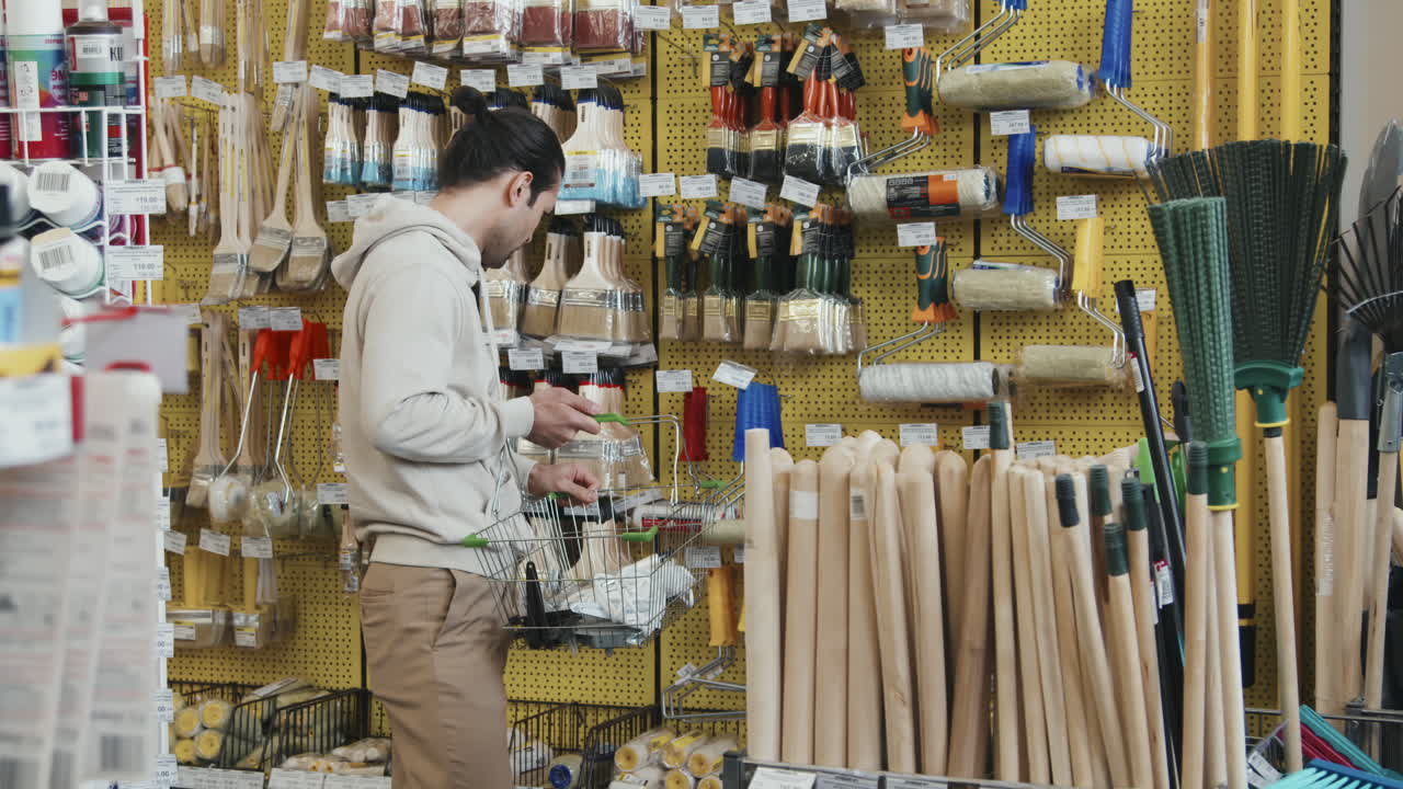 Slowmo of Man Shopping for Paintbrush and Paint Roller at Store