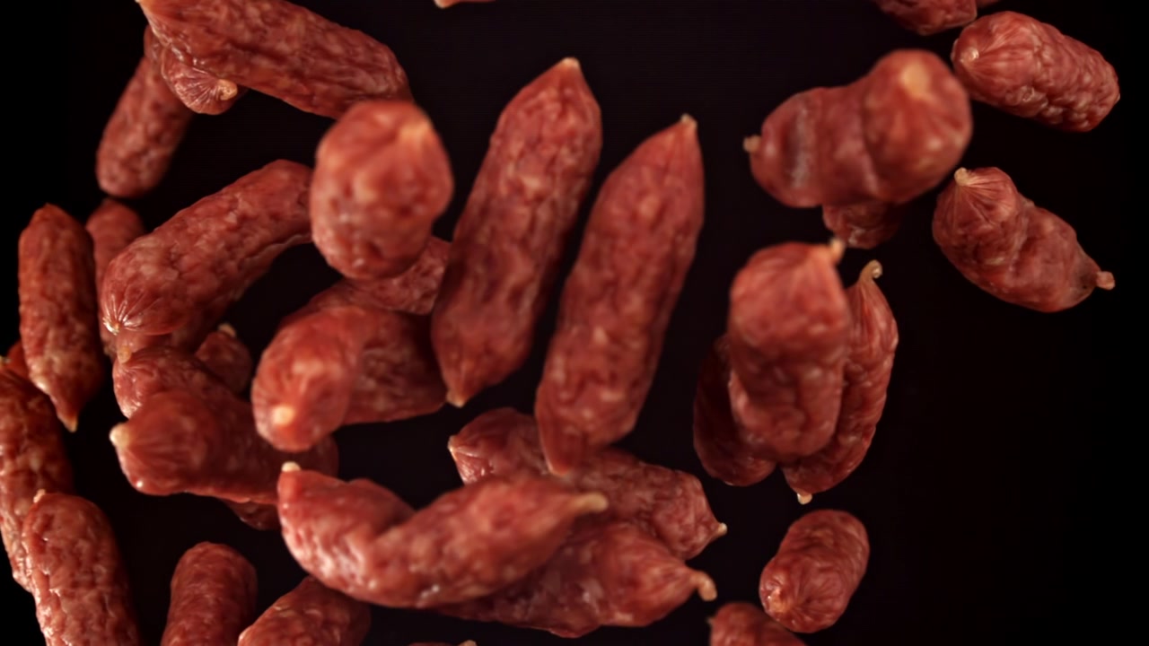 Pyszne mini kiełbaski salami spadające w zwolnionym tempie.