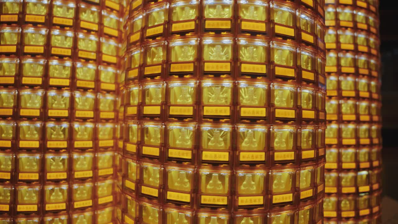 A symmetrical view of golden Buddha statues glowing in individual illuminated niches at Ciyou Temple in Taiwan, symbolizing devotion, peace, and spiritual reverence in a sacred Buddhist space