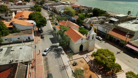 Aerial-reveal-of-Punta-de-Piedra-Church-in-Isla-de-Margarita,-Venezuela,-near-the-Caribbean-Sea-with-boats-at-the-dock