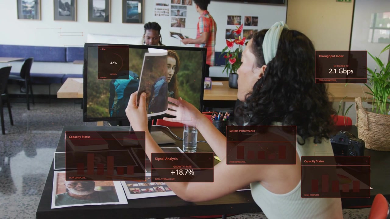 Lifting print, designer aligning, comparing to monitor for review while HUD panels updating charts
