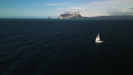 aerial tracking shot of a sailboat on the gulf of alaska with kayak island in the background