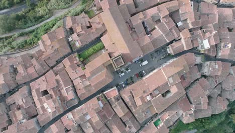 top down aerial drone view of the hilltop medieval town of pitigliano, tuscany in morning light, with red tile roofs and old buildings, in 4k