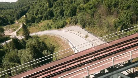 volando rápido con un dron fpv en serpentina con un viejo puente ferroviario que pasa por un camión largo blanco con un tanque de combustible y un camión conduciendo en dirección opuesta