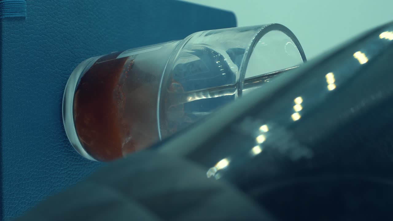 un primer plano vertical, llenando agua de vapor caliente en un vaso con café negro y azúcar moreno, granos de café flotantes, luz de estudio, video de 4k